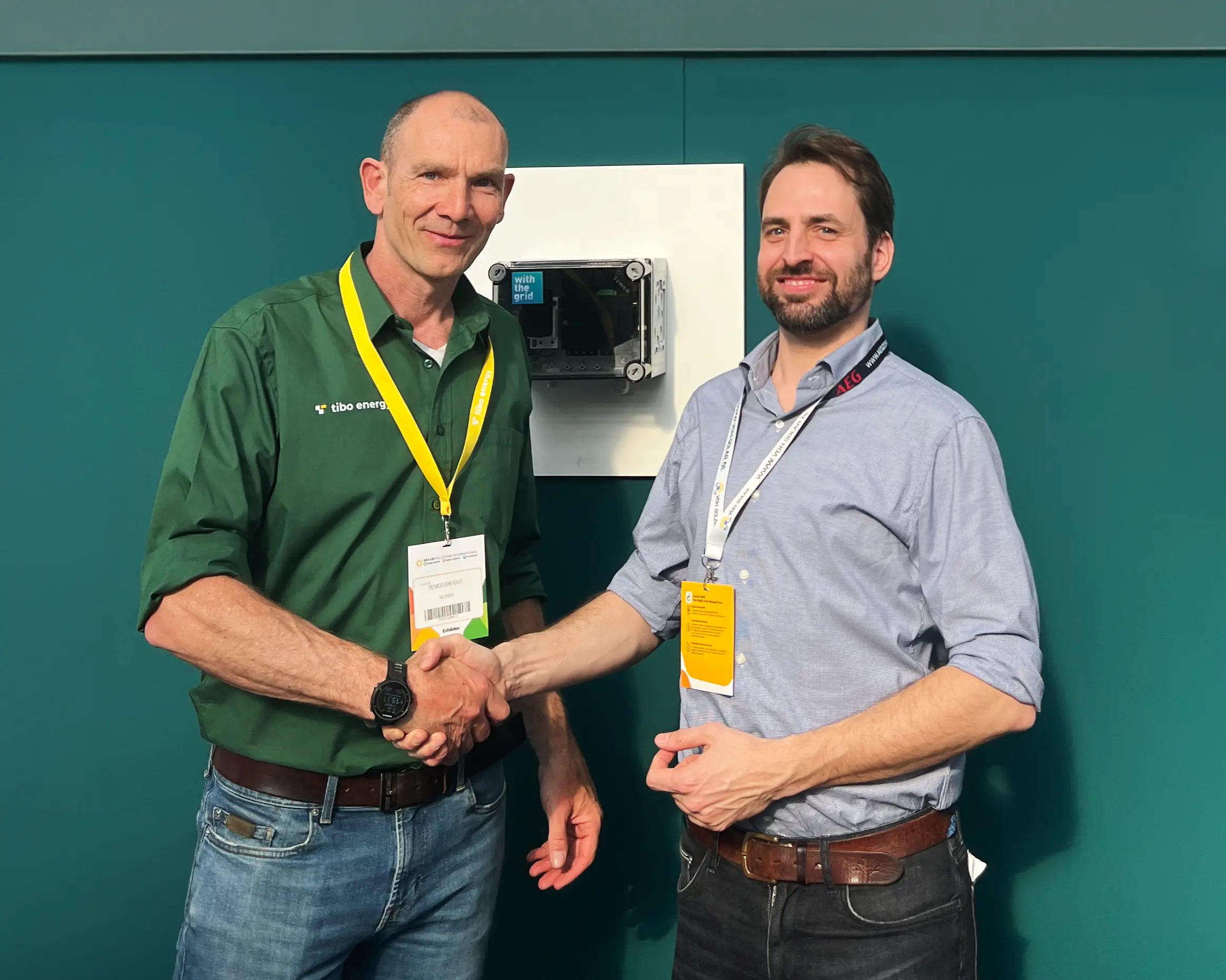Picture of Paul Mignot (CEO of Withthegrid) and Remco Eikhout (CEO of Tibo Energy) shaking hands at the Solar Solutions fair after signing their partnership agreement